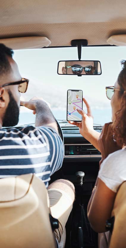 Couple in car looking at cell phone map directions