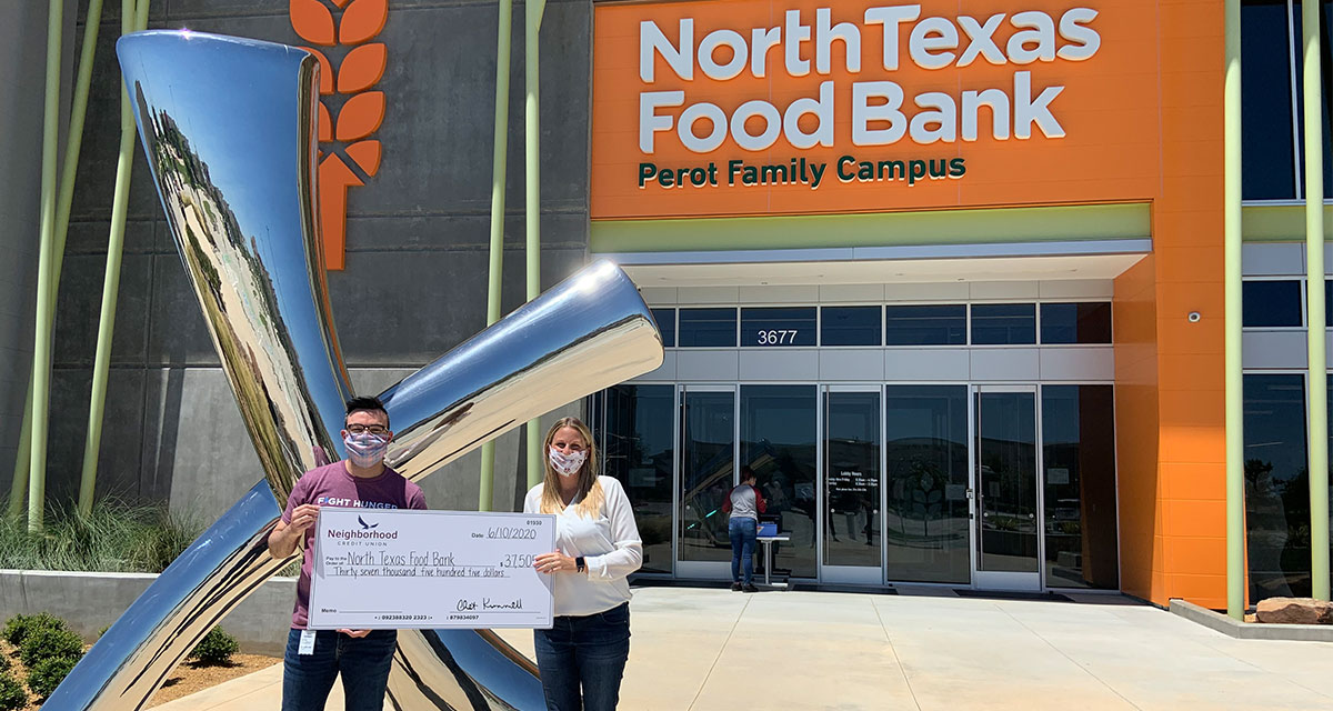 North Texas Food Bank Major Gifts Officer; Cody Meyers, and Neighborhood Credit Union VP, Marketing & Communications; Jessie Swendig. both are holding a check to the food bank in front of a silver statue.