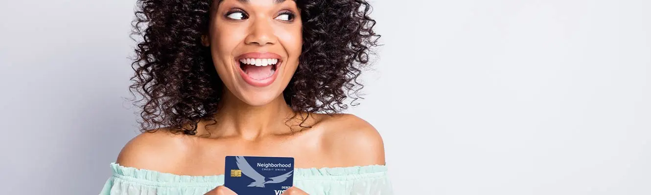 An image of a young woman with curly hair smiling and looking up at her neighborhood CU card. 