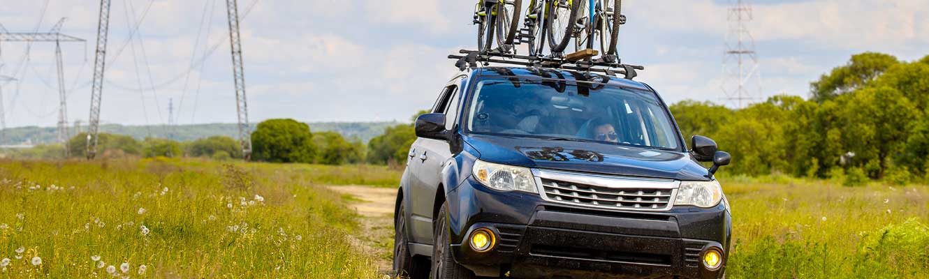 Image of an off roading vehicle with bikes on top in a back road area 